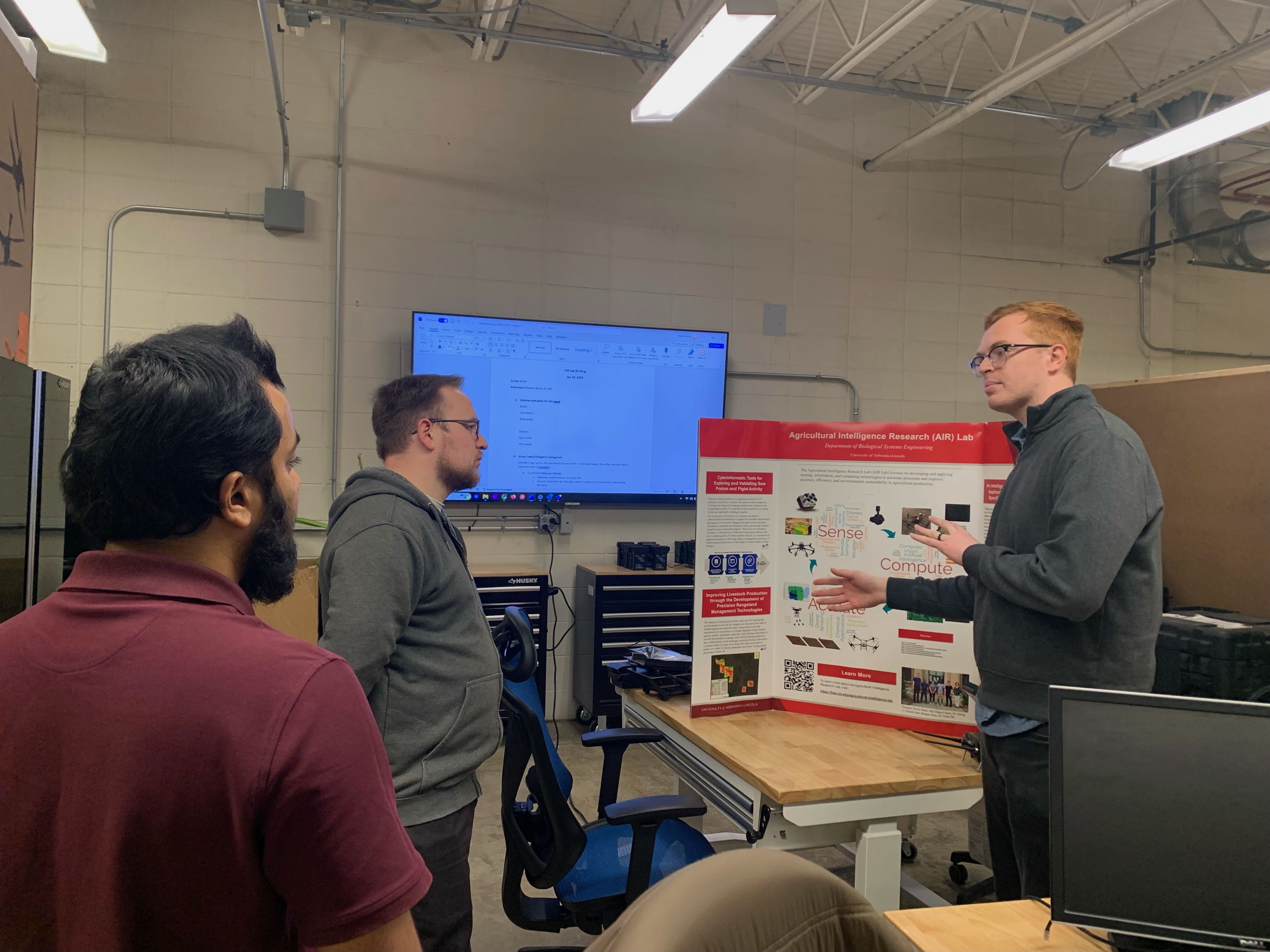 Image of Timo Becker in the middle of two University of Nebraska-Lincoln students, listening to a presentation about their lab research