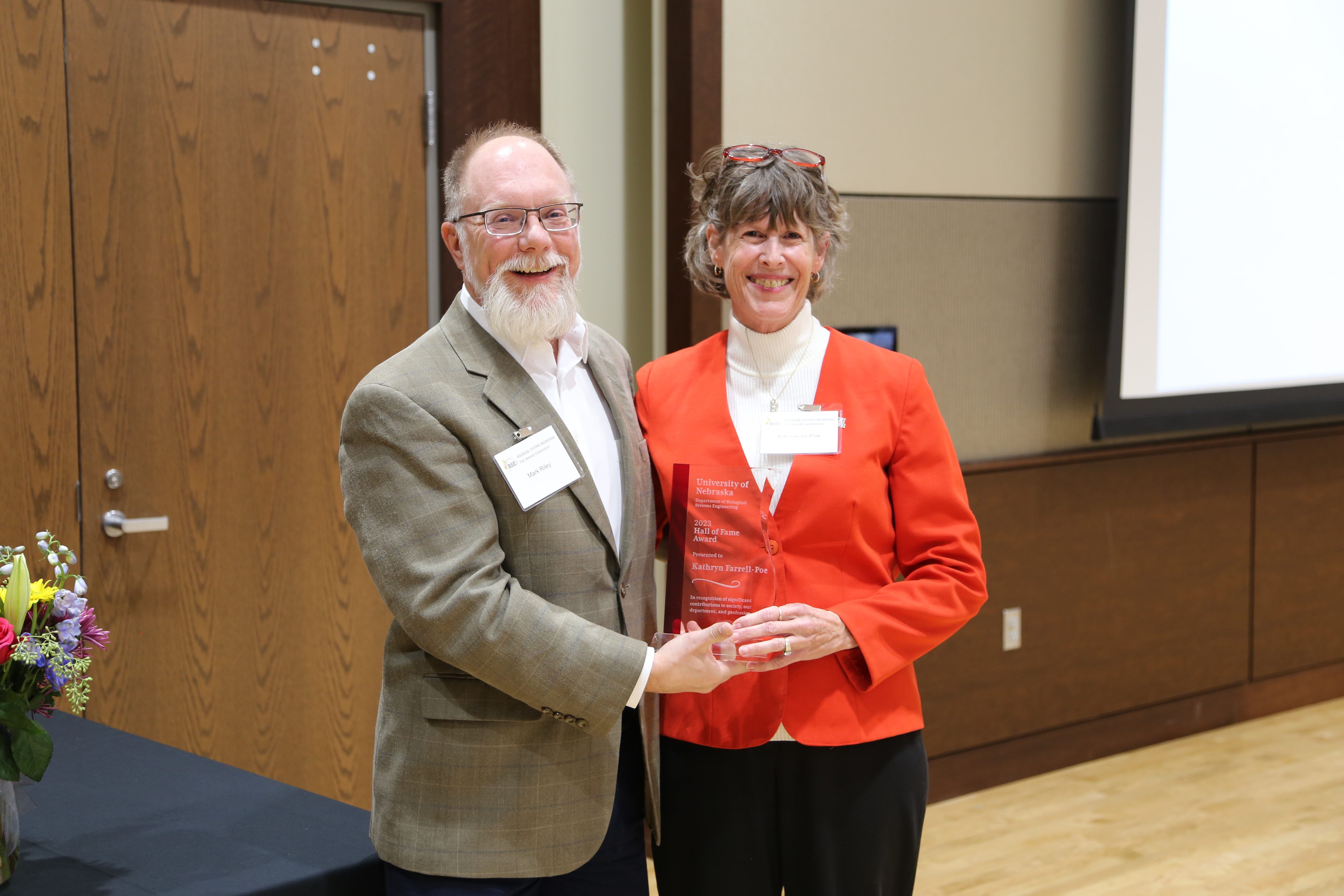 two people holding an award smiling at the camera