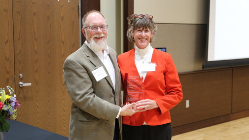 two people holding an award smiling at the camera