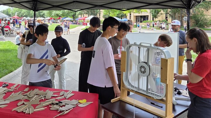 Teenagers building and testing wind turbines near a box fan