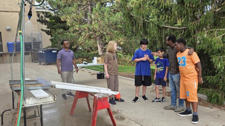 Middle school students discussing water run-off experiment with graduate students behind Chase Hall