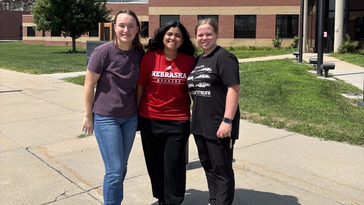 three students stand in front of powerplant