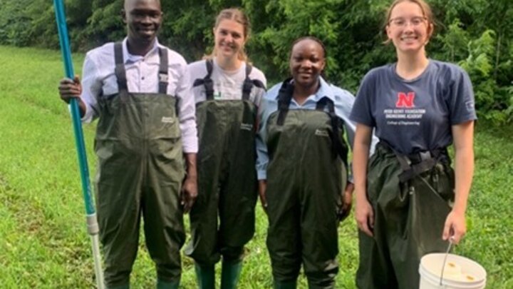 4 students in high-waders by the side of a wetland