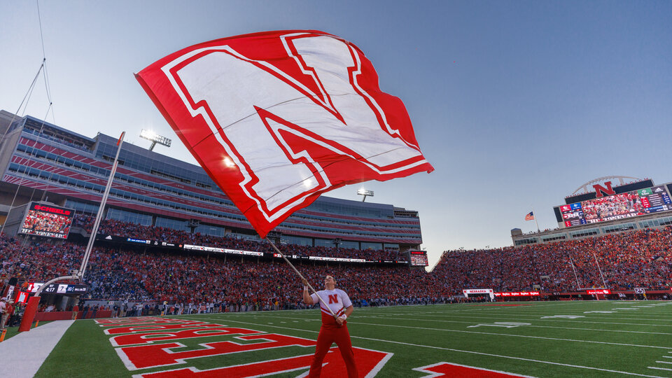 student waving University of Nebraska Flag in memorial stadium