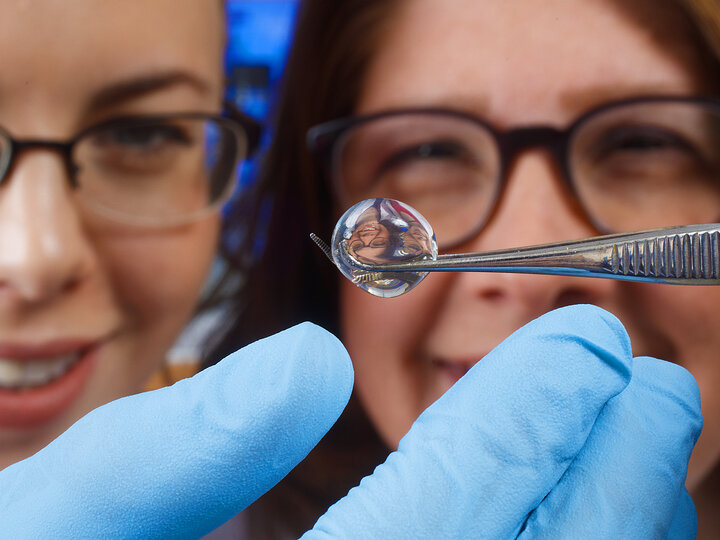 closeup shot of two people starting at a liquid substance in a lab