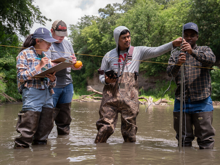 4 people in a lake conducting water quality experiments